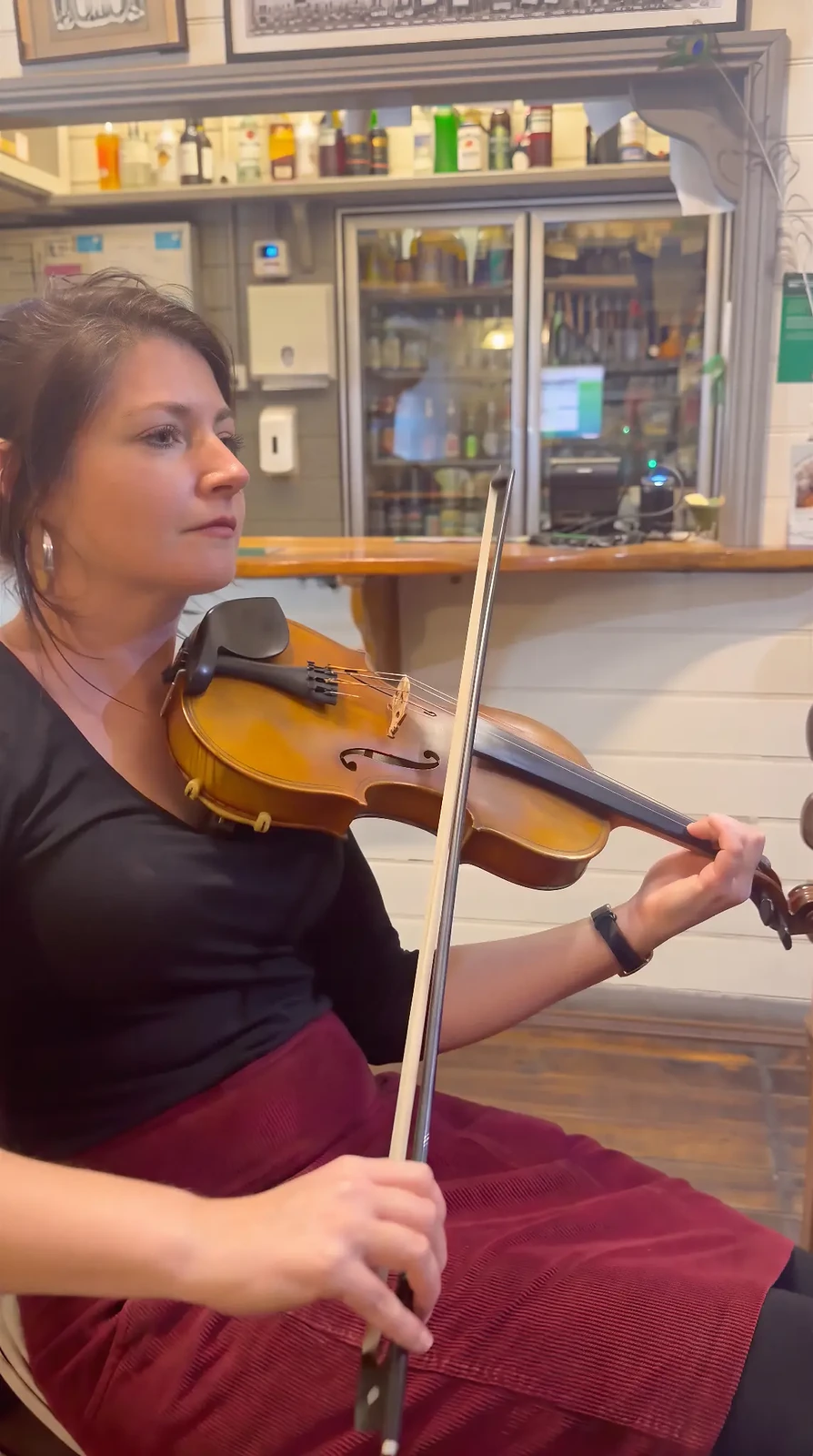Carmen playing fiddle in the corner of the bar