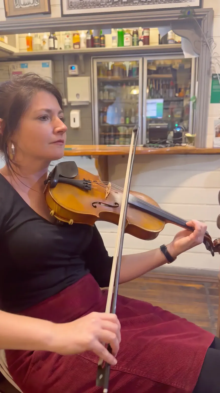 Carmen playing fiddle in the corner of the bar