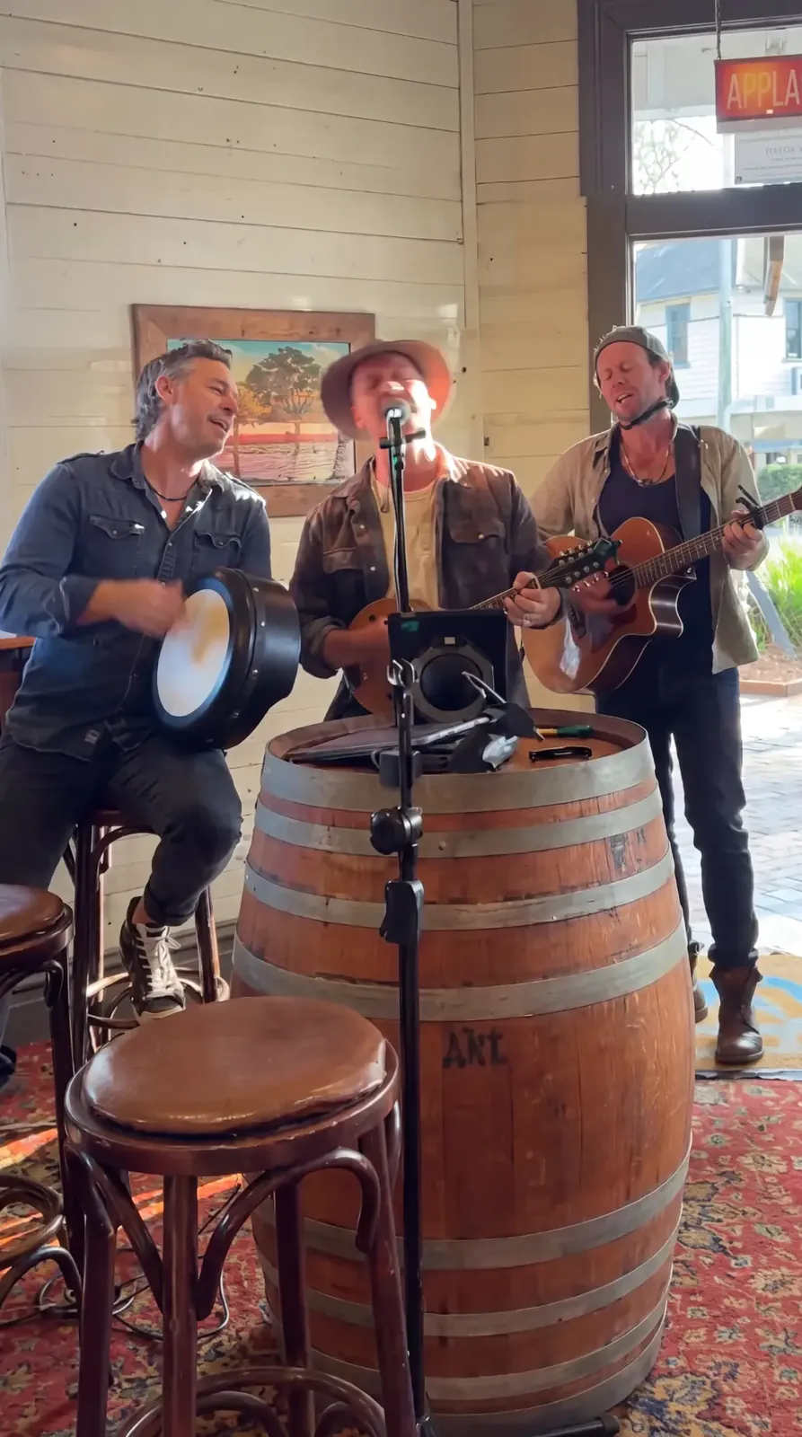 Three of the band singing around the barrel